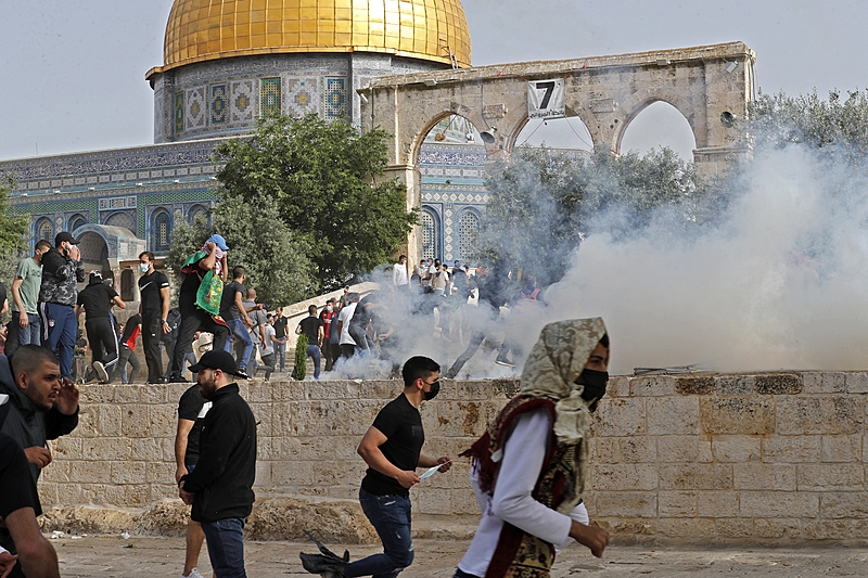 Palestinos se esquivam de granadas lançadas no entorno da mesquita de Al-Aqsa | Foto: Ahmad Gharabli / AFP