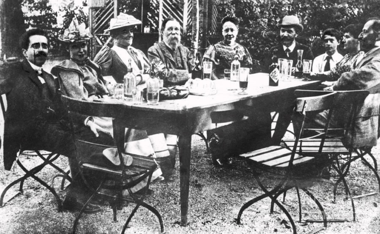 Fundadora do Partido Comunista da Alemanha e líder do movimento internacional das mulheres, Clara Zetkin escreve sobre o falecimento de Friedrich Engels. Na foto, Zetkin aparece ao lado de Engels em almoço promovido por August Bebel.