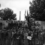 Metalúrgicos fazem greve e ocupam fábrica nos subúrbios de Paris, 1936. Trabalhadores posam com punhos erguidos e jornal L’Humanité durante as greves alegres que marcaram a história operária francesa. 📷 Foto: Agência Meurisse / Domínio Público via Wikimedia Commons