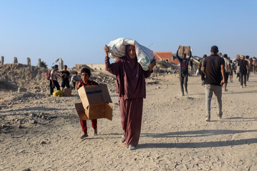 Palestinos carregam caixas e sacos de ajuda humanitária na Cidade de Gaza, em 16 de junho de 2025. (Foto: Rizek Abdeljawad/Xinhua)