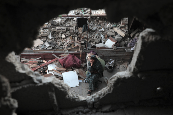 Palestina sentado entre escombros de prédios destruídos por ataques israelenses na cidade de Khan Younis, no sul da Faixa de Gaza, em 13/10/2025. Foto: Rizek Abdeljawad/Xinhua