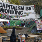Banners do protesto Occupy London em Finsbury Square, com críticas ao capitalismo e apelos por alternativas sociais, em 5/11/2011. Foto: Alan Denney/Wikimedia Commons (CC BY-SA 2.0).