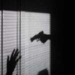 Sombra de uma mão armada apontada para outra mão em gesto de rendição. Foto: Maxim Hopman / Unsplash – Publicada em 19 de novembro de 2020 – Canon EOS 6D Mark II – Uso gratuito sob a Licença Unsplash.