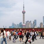 Turistas caminham pelo Bund, em Xangai, no leste da China, com vista para o distrito financeiro de Pudong ao fundo, em 30/04/2023. Crédito: Xinhua / Xin Mengchen