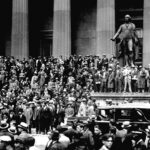 Multidão em frente à Bolsa de Nova York durante o “Black Thursday”, 24 de outubro de 1929. O pânico financeiro marcou o início da Quebra da Bolsa e da Grande Depressão, que se espalhou para a Europa e desestabilizou economias em todo o mundo. Crédito: Associated Press / Domínio público — via Wikimedia Commons
