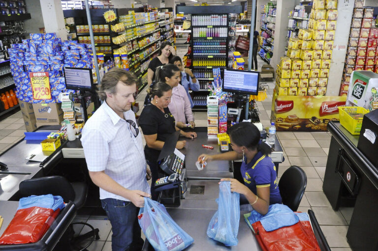 Trabalhadora do Supermercado São Luiz, em Planaltina, Distrito Federal, atende consumidores em supermercado, com prateleiras e produtos ao fundo. Foto: Edilson Rodrigues/Agência Senado