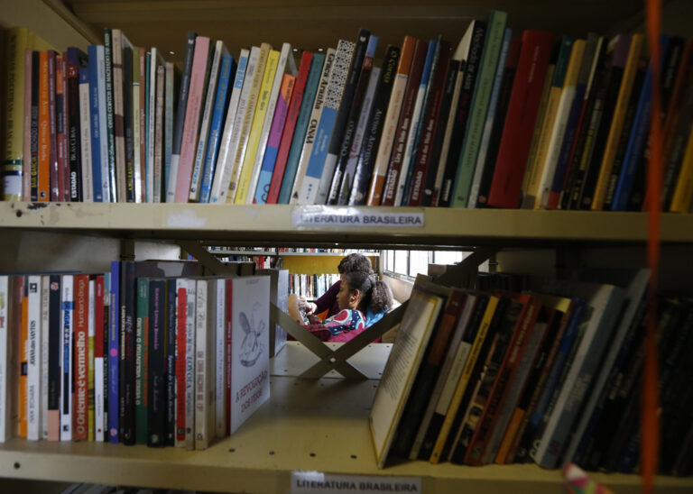 Crianças participam de atividade de leitura mediada em biblioteca comunitária com estantes de livros, em São Paulo, simbolizando o acesso à leitura e a formação de leitores. Foto: Paulo Pinto/Agência Brasil