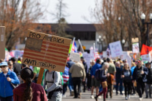 Manifestação do No Kings em Springfield, Oregon, mostra participante com cartaz crítico a Trump em meio a multidão durante protesto nacional nos Estados Unidos. Foto: David Geitgey Sierralupe / Flickr (CC BY-SA 4.0)