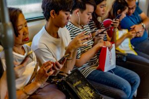 Passageiros utilizam smartphones em transporte público. A captura da atenção e o uso de dados pelos algoritmos são temas centrais do debate sobre o poder das Big Techs. Foto: John Lockwood/Unsplash.